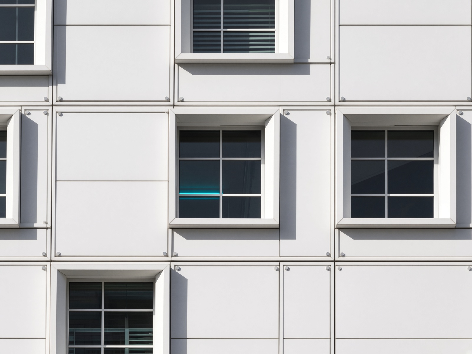 Close-up of the white facade grid, hard noon shadows on enamel, a hint of interior neon.